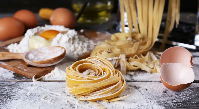 Fresh pasta nests with eggs, flour and a pasta machine