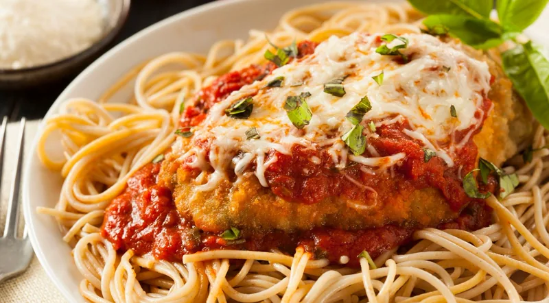 A plated Roman pasta dish with tomato sauce and basil