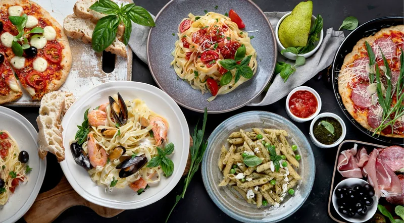 A spread of Italian pasta dishes and pizza on a table